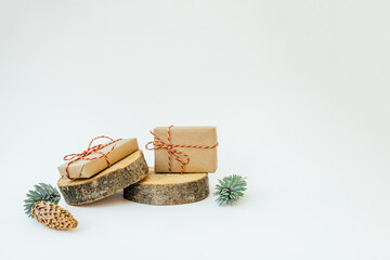 Two craft gifts on the wooden round cylinders shapes on the light background. Concept Christmas and New Year. Copy space.