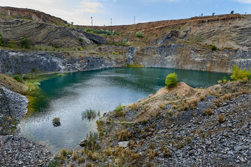 Lake in an ancient quarry with various types of rocks