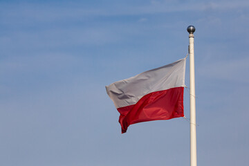 Polish flag waving against the background of the blue sky
