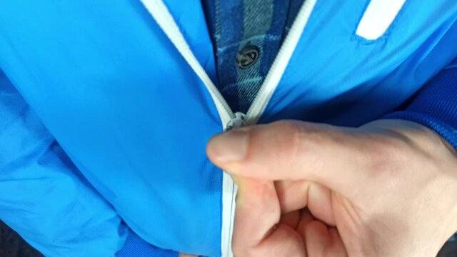 Man wearing trendy blue jacket with zipper. Young man is zipping up jacket. Cold weather concept. Winter is coming.