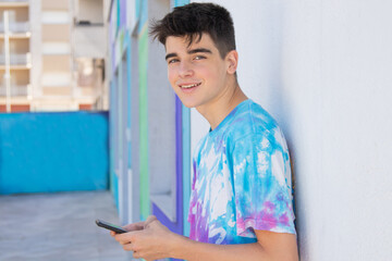 male teenager with mobile phone on the street outdoors in the city