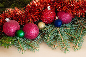 Christmas decoration on a wooden textured background. Ornaments arranged creatively around borders with spruce leaves. Congratulations on the upcoming season. Flat position or top view.