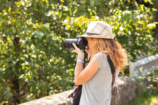 woman with photo camera taking photos in nature
