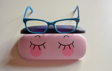 Rectangular glasses in bright blue frames on a funny case for glasses light background close-up