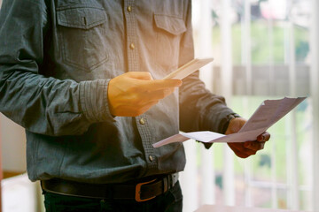 Man checklist using bank of credit card by mobile phone and pay bills in the office	