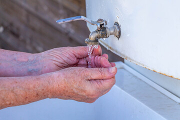 An elderly woman washes her hands.