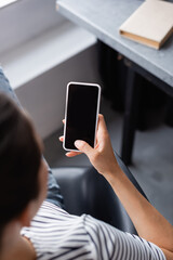 Overhead view of young woman using smartphone with blank screen at home