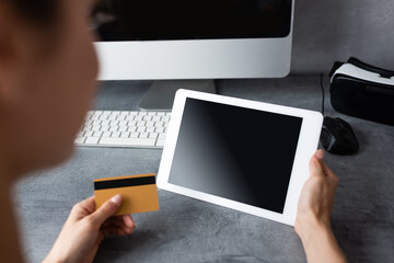 Selective focus of teleworker using digital tablet and credit card near computer on table