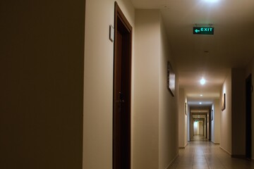 long interior corridor with many doors and exit signs
