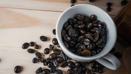 Coffee beans in white cup on wood table for food and drink content.