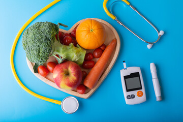 World diabetes day. National American diabetic awareness. Free Glucose Monitors on blue background. Yellow stethoscope check fruit on heart plate. Healthcare and medical concept