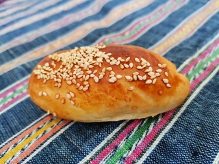 Close-up breakfast bun with sesame and olives.