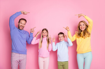 Photo of surprised mommy daddy small kids point index finger empty space isolated over pastel color background