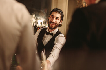 Smiling bartender serving drinks to guest