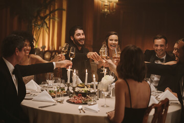 Multi-ethnic people celebrating with drinks at dinner party
