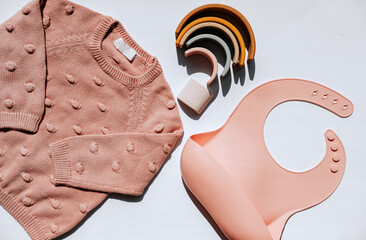 Set for girls, pink sweater, silicone bib and toy rainbow. High quality photo