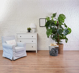 Decorative white cabinet and blue armchair, vase of plant and blanket style, brick wall background.