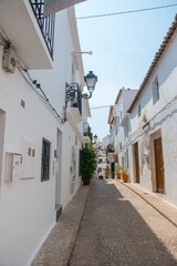 Beautiful narrow street in Altea, Costa Blanca, Valencian Community, Spain. Historical center. Stone stairs going up. Vertical shot. White architecture. Nobody in the street. 