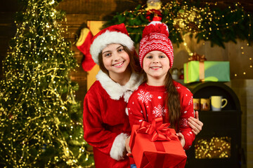 Sisterhood and family. Boxing day. Children picking gifts for family. Small girls preparing holiday gift. Receiving presents. Christmas gift for sister. Kids little cheerful girls hold gift box