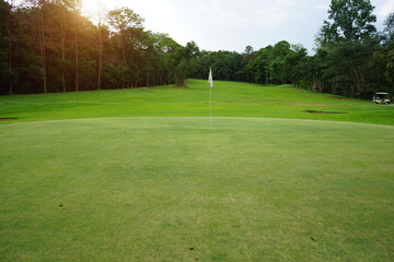 Obraz premium Background of evening golf course has sunlight shining down at golf course in Thailand. Nice scenery on a golf course at a late summer afternoon