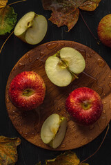 Fresh red apples with maple leaves on a wooden background