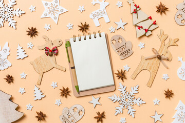 Festive decorations and toys on orange background. Top view of notebook. Merry Christmas concept