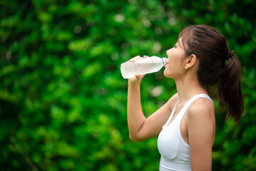 Asian young woman drinking water after workout exercising.