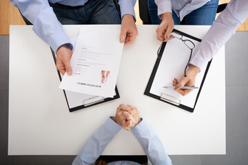 Top view of white table and people with legal pad and cv during recruitment interview