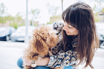 Caucasian woman looking happily at her little dog. Copy space. Love for animal concept.