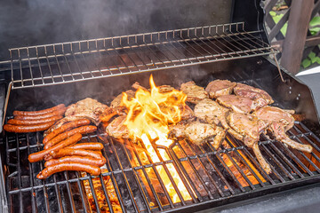 Tomahawk rib beef steak ans sausages on hot black grill with flames bbq