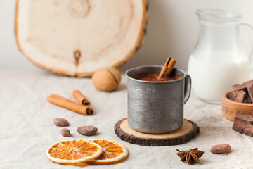 Hot chocolate in a metal mug with a cinnamon stick on the tablecloth. Copy space