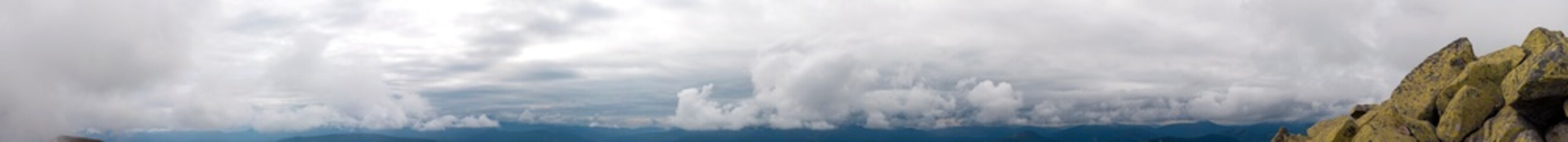 Panorama of mountain peaks. Panorama of rocky placers and storm clouds