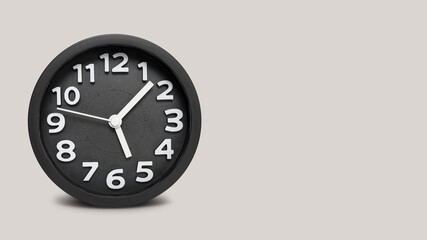 Closeup black round alarm clock on grey background with copy space,.Time concept with black clock at Five O' clock and 5 minute, Concept of time countdown deadline,Symbol time alarm to end of work day