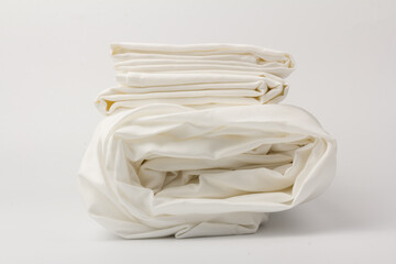 Stack of clean bed sheets on white  background, closeup.