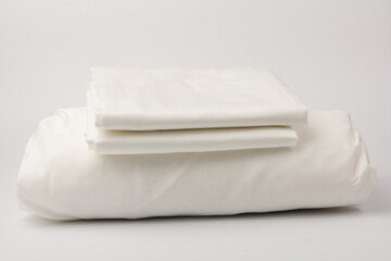Fototapeta na wymiar Stack of clean bed sheets on white background, closeup.