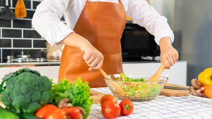 woman in the process of preparing healthy food Vegetable Salad mixing salad wooden spoon in kitchen at home Dieting Concept