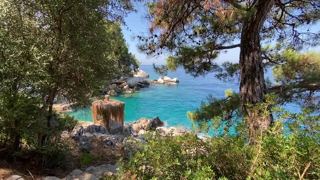 Turquoise Mediterranean Sea and rocky green island with pine trees. Beautiful clean blue sea water and skies, green trees and a boat on the water.