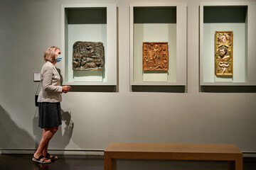 woman stading in a room looking and pointing at the empty frames displayed