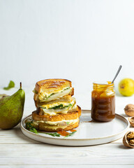 Homemade cheese melt sandwich with pears and arugula served with caramel sauce