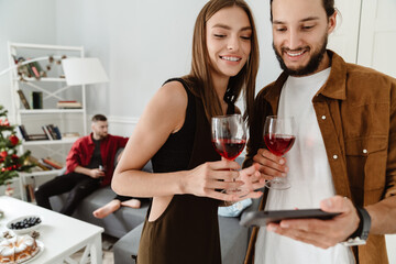 Image of multinational friends using mobile phone while drinking wine