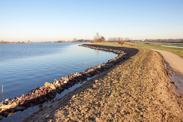 Recently reenforced dike with rubble to protect the shoreline (left), a raised clay-bar to prevent...