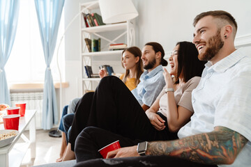Obraz premium Image of friends drinking beverage and eating popcorn while watching movie