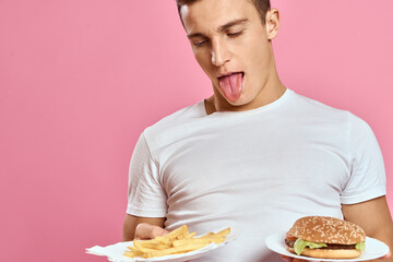 Guy hamburger fries and shows tongue on pink background