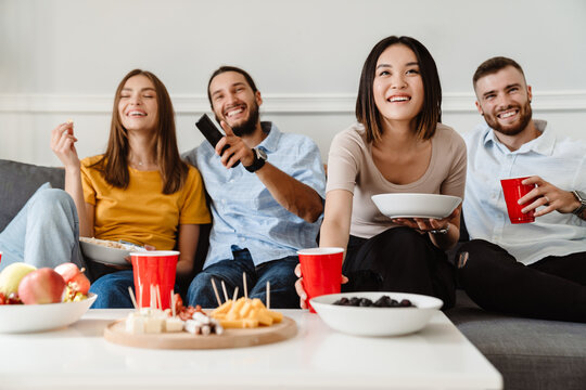 Image of friends drinking beverage and eating appetizer while watching tv
