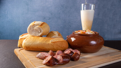 Breads, vinaigrette, sliced ​​roasted sausage and a glass of beer on a table, blue background, selective focus.
