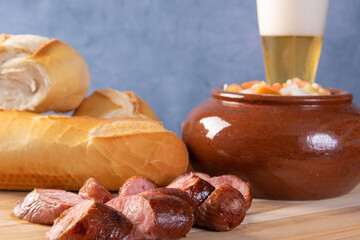 Breads, vinaigrette, sliced ​​roasted sausage and a glass of beer on a table, blue background, selective focus.