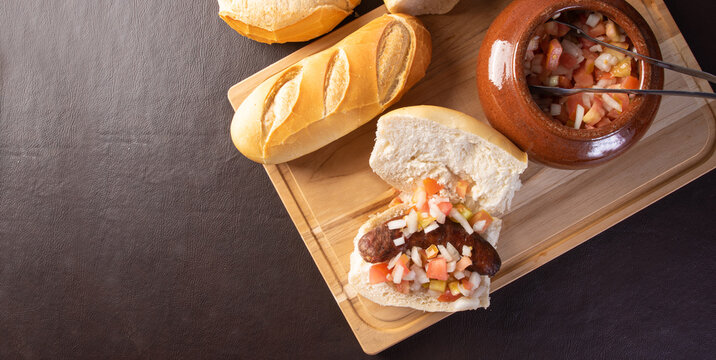 Bread with roasted sausage and vinaigrette on a table, top view.