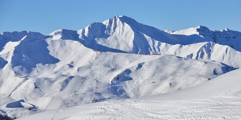 Fototapeta na wymiar Panoramic view of the snowy high-altitude mountain range with ski piste and lifts near the Tignes ski resort in France during the winter season.