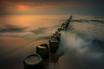 Sunset on the Baltic Sea and old wooden breakwater