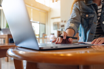 Closeup image of a woman writing and working on laptop computer in office